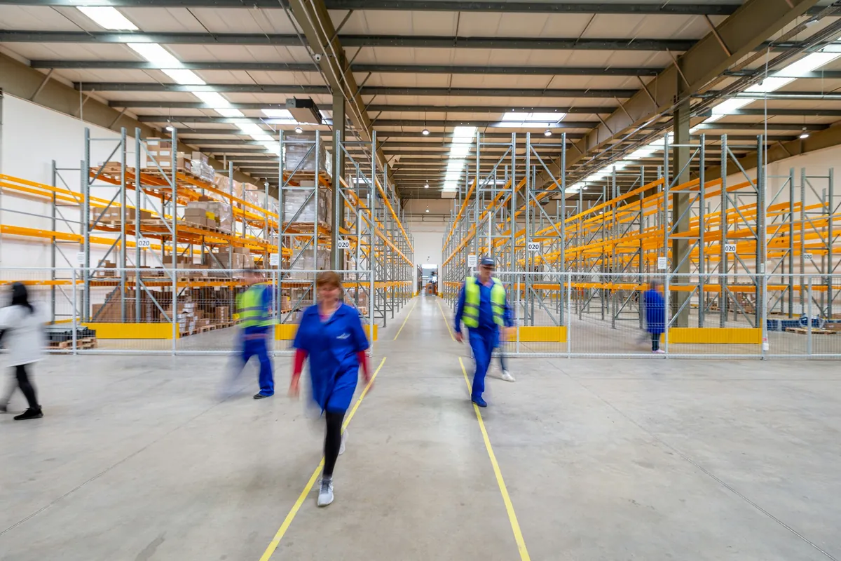 Workers moving through a warehouse aisle