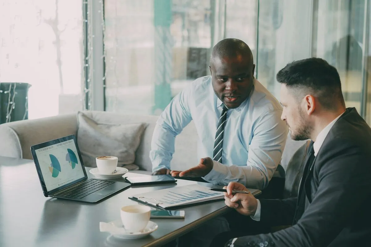 Two bankers reviewing reconciliation charts on a laptop