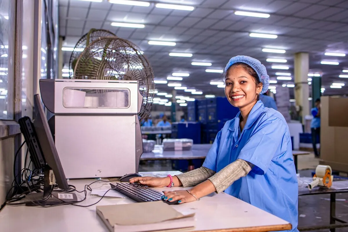 Factory worker logging production at a computer on the floor