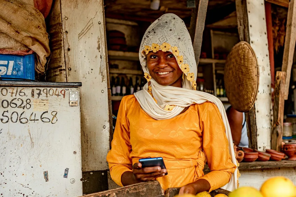 Market vendor checking a payment on her phone at her stall