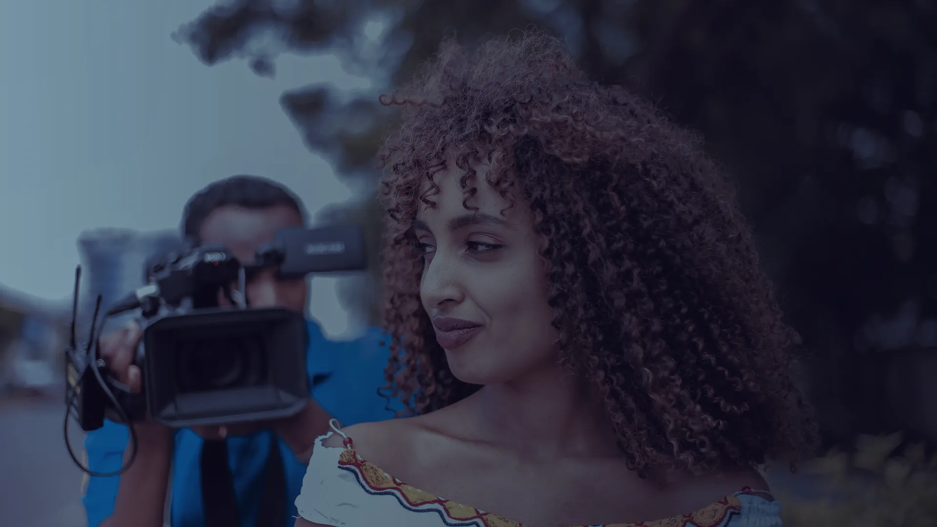 Camera operator filming a presenter outdoors